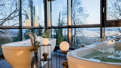 Luxuriöse Badewannen mit Blick auf Fenster und Bäume bei Dämmerung