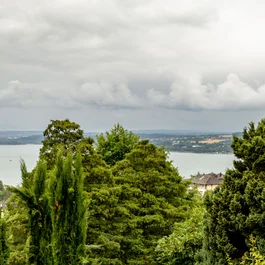 Paar umarmt sich auf Balkon mit Blick auf bewölkten Himmel und Landschaft