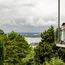 Paar umarmt sich auf Balkon mit Blick auf bewölkten Himmel und Landschaft