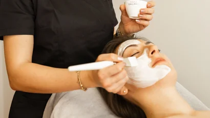 Kosmetikerin trägt Gesichtsmaske bei einer entspannten Kundin im Spa auf