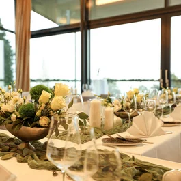Eleganter festlich gedeckter Tisch mit Blumenarrangements und Kerzen am Fenster