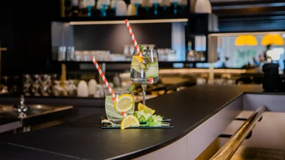 Zwei Gläser mit Zitronenwasser und Strohhalmen auf einer Bar mit unscharfem Hintergrund