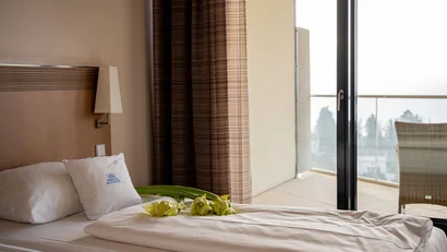 Modernes Hotelzimmer mit weißem Bett und Balkon mit Stuhl