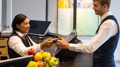 Hotelrezeptionistin übergibt Schlüssel an Gast an der Rezeption