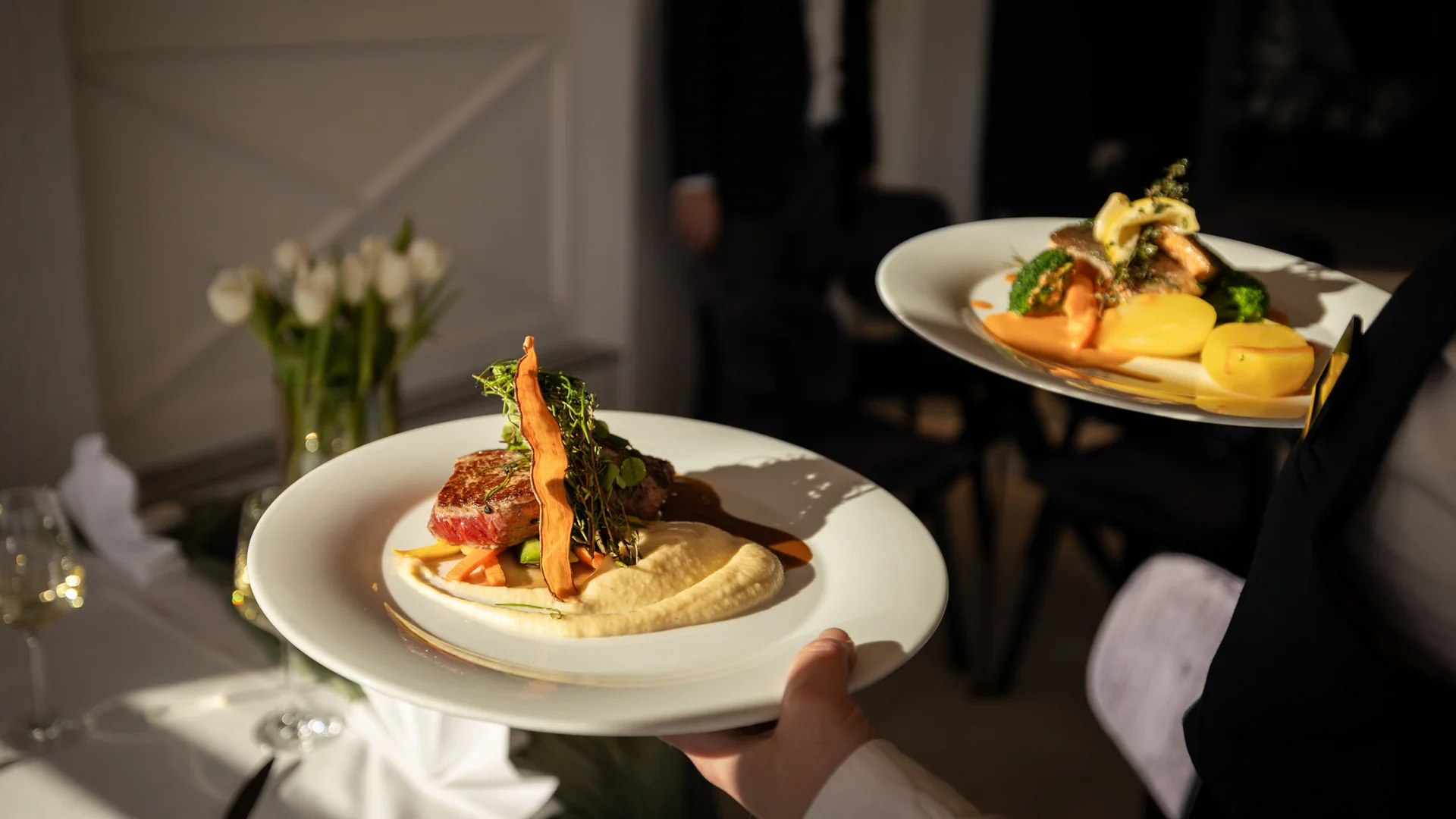 Zwei Teller mit Gourmetgericht werden von Kellner serviert