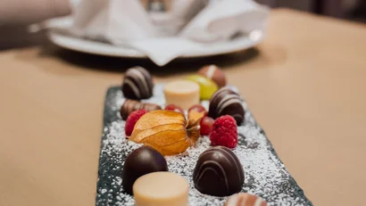 Pralinen und Beeren auf einem Teller mit Champagnerkühler im Hintergrund
